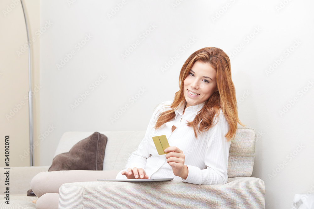 Young girl thinks about purchasing through the internet sitting on the sofa Young girl thinks about purchasing through the internet sitting on the sofa
