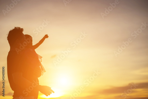 Father took the baby learn to walk at sunset.