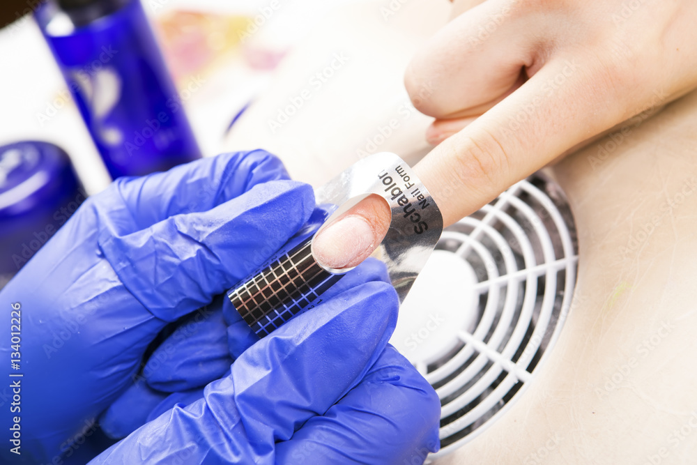 Manicure specialist care by finger nail in beauty salon. Manicurist uses professional manicure tool. Use of a template (schablon) for acrylic nails Manicure specialist care by finger nail in beauty salon. Manicurist uses professional manicure tool. Use of a template (schablon) for acrylic nails