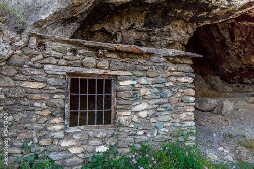 Fototapeta Naklejka Na Ścianę i Meble -  Entrance of a cave next to a stone house