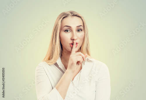 Woman wide eyed asking for silence or secrecy with finger on lips