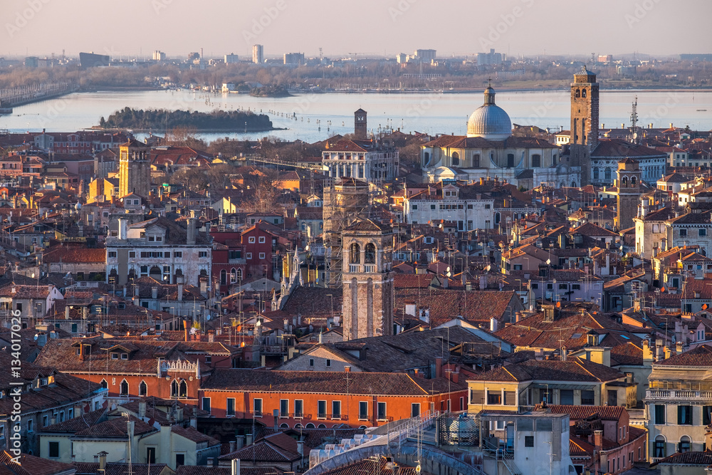 Aerial view of Venice, Italy, at sunset with rooftops of building, the sea and warm sunlight.