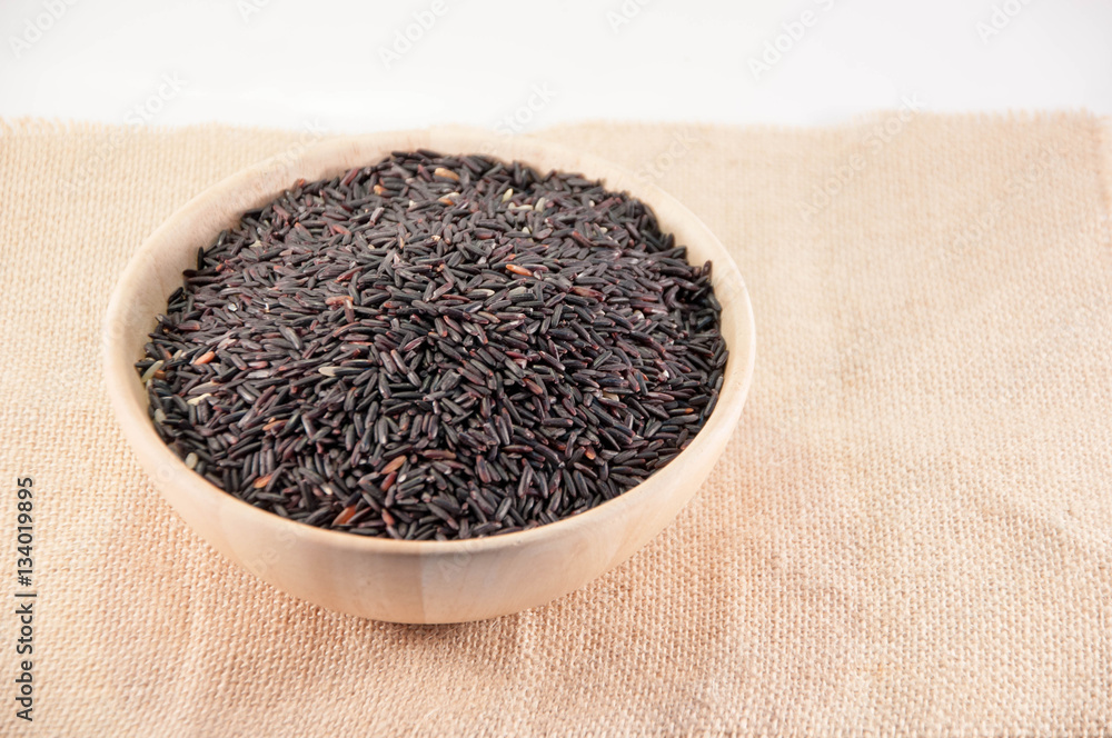 The purple rice in wooden bowl on sack fabric. Natural rice. Organic rice. object. background. The purple rice in wooden bowl on sack fabric. Natural rice. Organic rice. object. background.