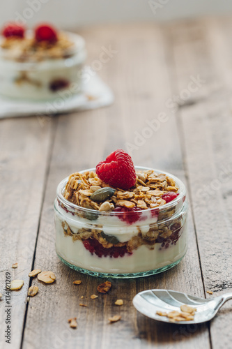 Homemade Granola with Yogurt and Raspberries on Wooden Table