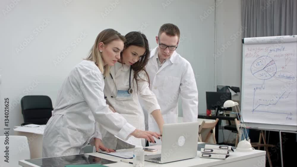 Team of doctors working on laptop and analyzing xray in medical office Team of doctors working on laptop and analyzing xray in medical office