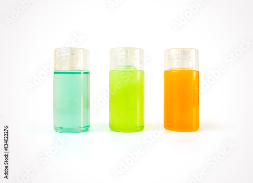 Three small plastic bottles full of colorful cosmetic products with copy space
