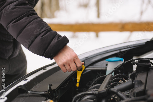 Car maintenance before winter. Man checking oil level in his car using dipstick. Outdoor closeup photograph © wstockstudio