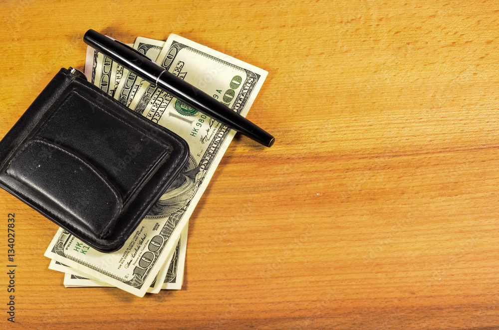Money clip and one hundred dollars banknotes on wooden table Money clip and one hundred dollars banknotes on wooden table