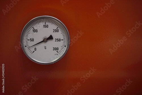 round metal device for measuring on an orange background