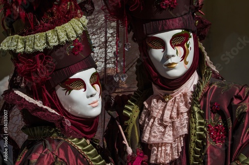 Picturesque photography of beautiful couple with colored costume and venetian mask during Venice Carnival symbol of tradition, refinement and artistic creativity