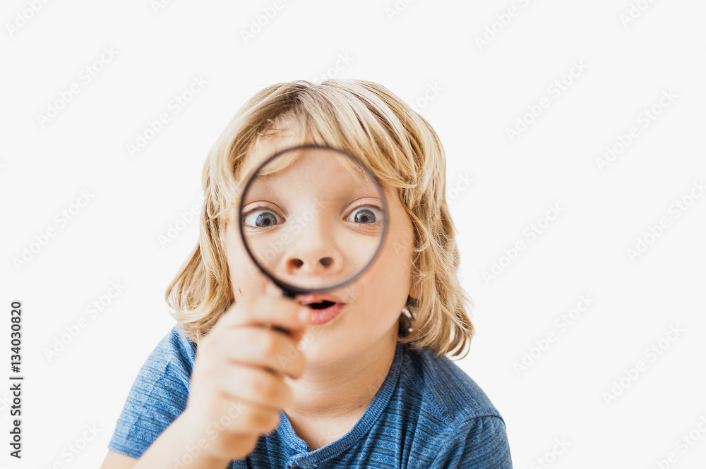 Funny little boy looking through a magnifying glass Funny little boy looking through a magnifying glass