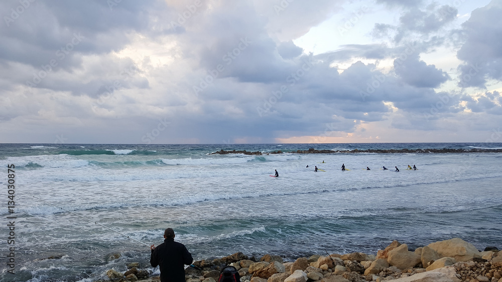 Fisherman and group of surfers