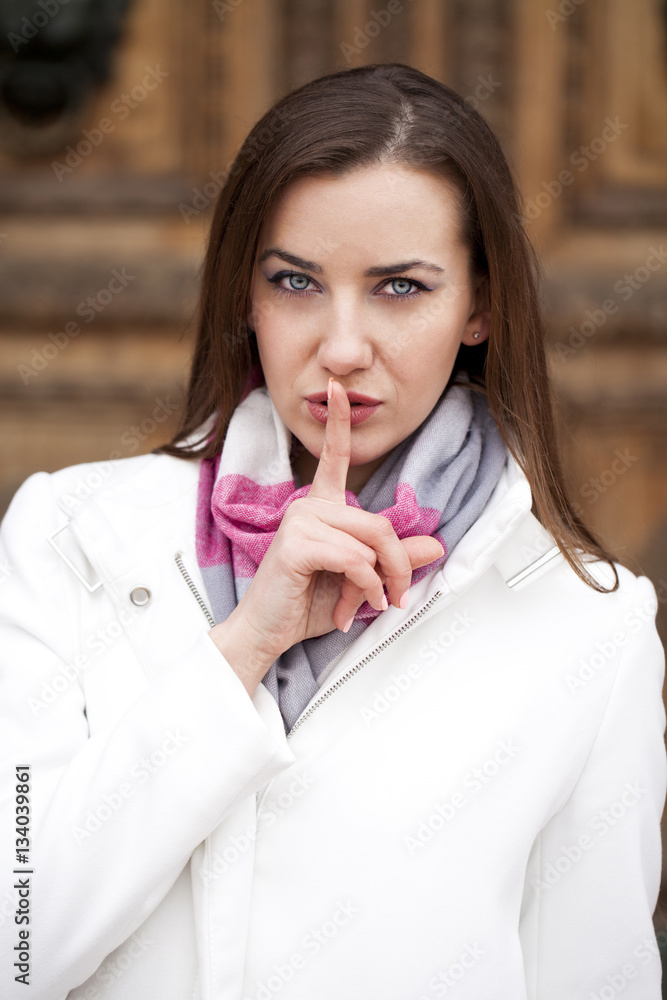 Portrait of attractive young woman with finger on lips