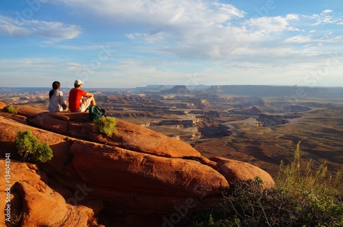 Two hikers enjoy the view form the Green River Overview, looking down into the valley carved by the Colorado and Green River. Canyonlands National Park, Utah, USA