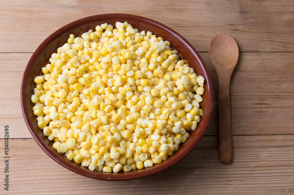 Frozen corn in a bowl with a wooden spoon Frozen corn in a bowl with a wooden spoon