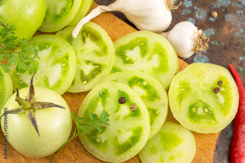 sliced green tomatoes with garlic and peppers on a wooden cuttin
