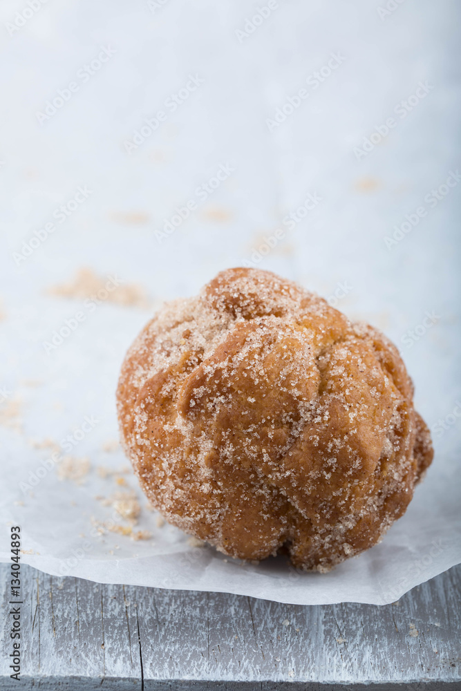 Donut hole rolled in cinnamon sugar on awhite paper. Donut hole rolled in cinnamon sugar on awhite paper.