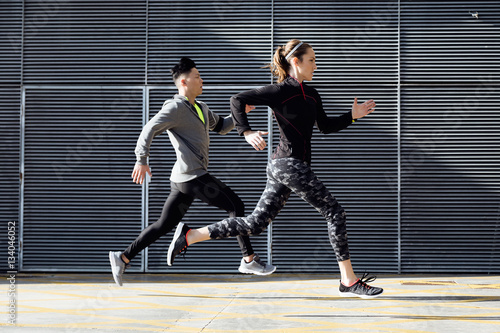 Fit and sporty couple running in the street.