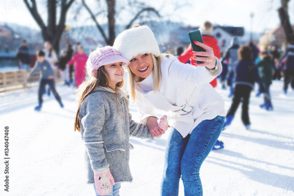 Mother and daughter taking selfy in skating ring.Colored photo Mother and daughter taking selfy in skating ring.Colored photo