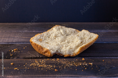 Big slice of white homemade bread on wooden table on black background.