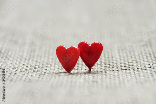 two red little hearts on the background of linen fabric