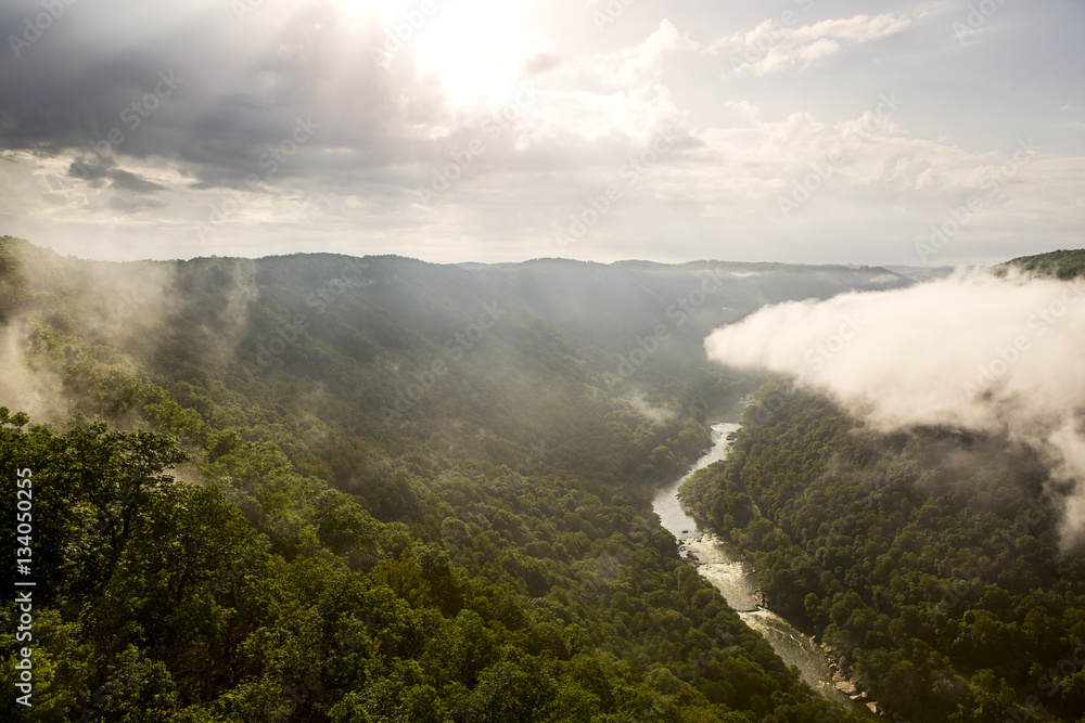 The sun rises over the New River Gorge on a misty, rainy morning in West Virginia.