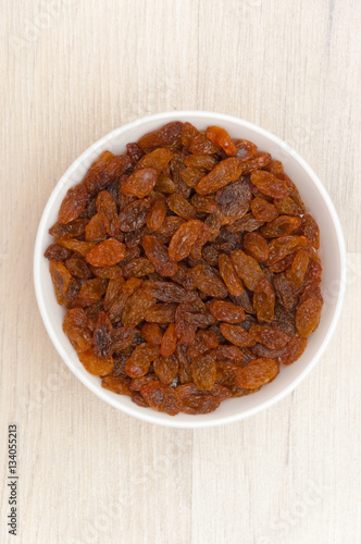 Raisins in white bowl or cup. Dried sweet berries.