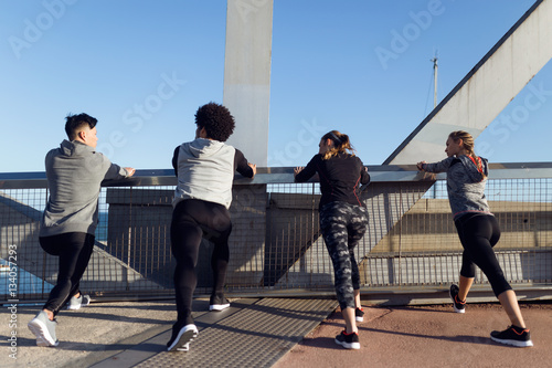 Portrait of running people doing stretching in the city.