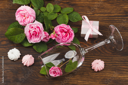Light pink roses and wineglass on the wooden table
