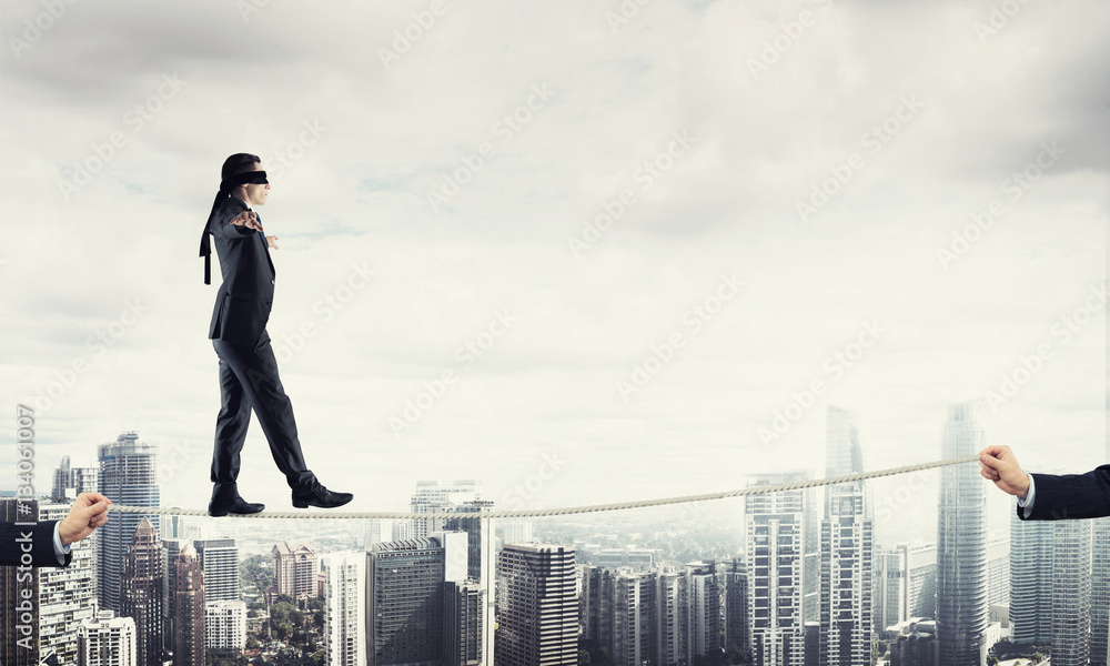 Business concept of risk support and assistance with man balancing on rope Business concept of risk support and assistance with man balancing on rope