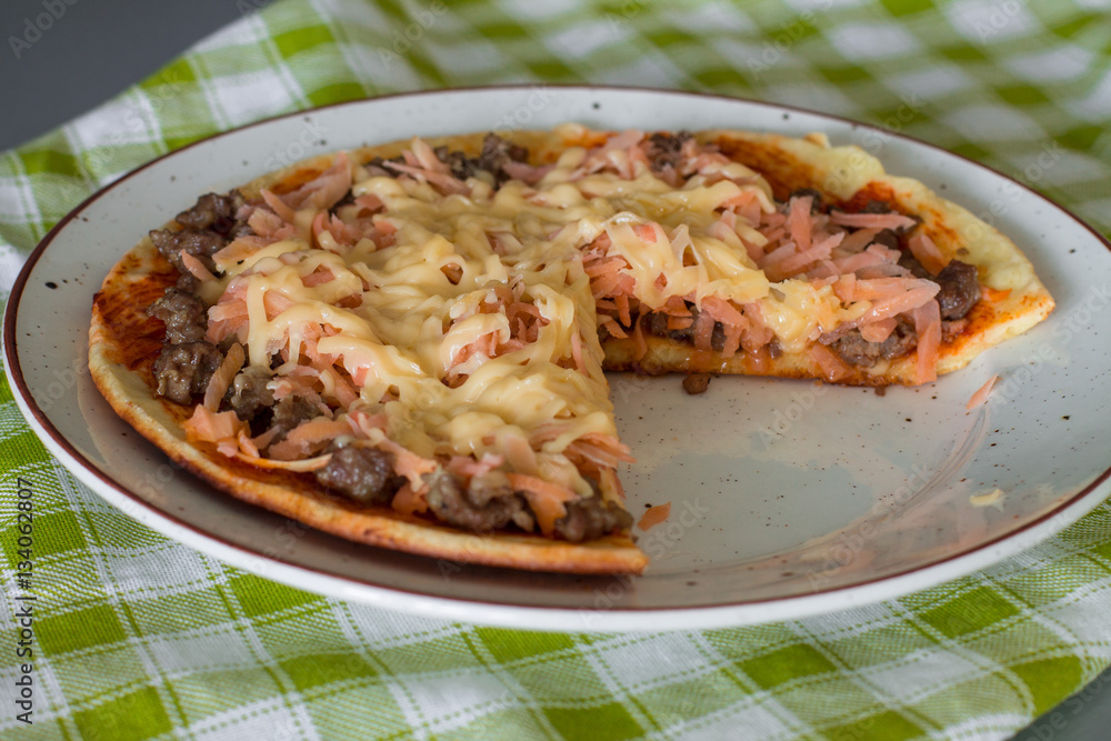 Cutting frittata with tomato sauce, carrot, fried minced beef and cheese on white plate on green checkered napkin. Cutting frittata with tomato sauce, carrot, fried minced beef and cheese on white plate on green checkered napkin.