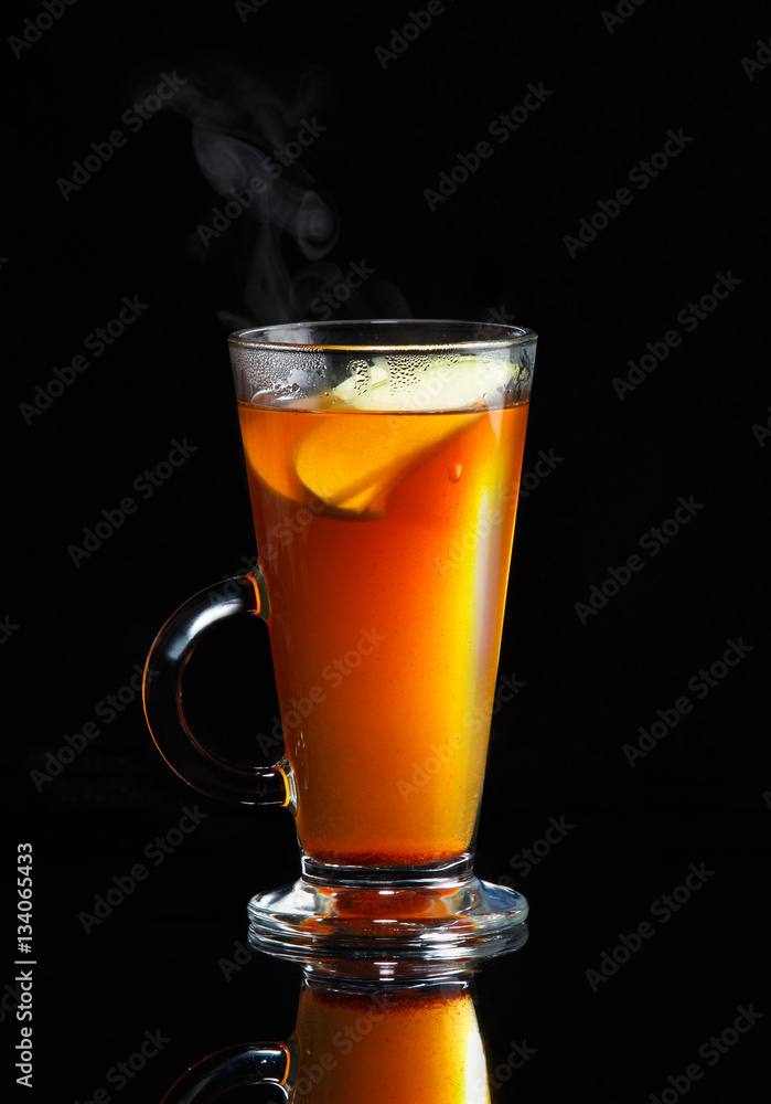 Hot steaming rooibos tea with apple slices on black reflective background Hot steaming rooibos tea with apple slices on black reflective background
