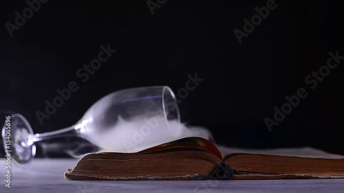 book with smoke and wine glass on dark background