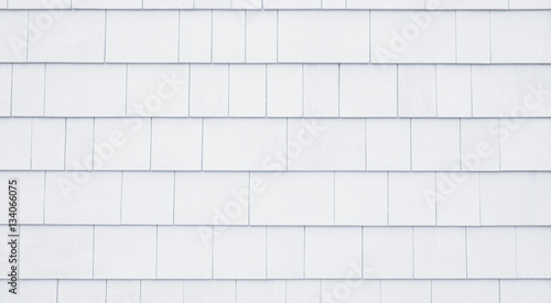 Neutral white or tan siding on a house or building. Straight parallel lines. Outdoor siding with highlights.. Roofing or construction material.