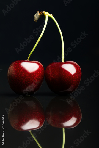 Fotografie Two juicy fresh cherries on black background