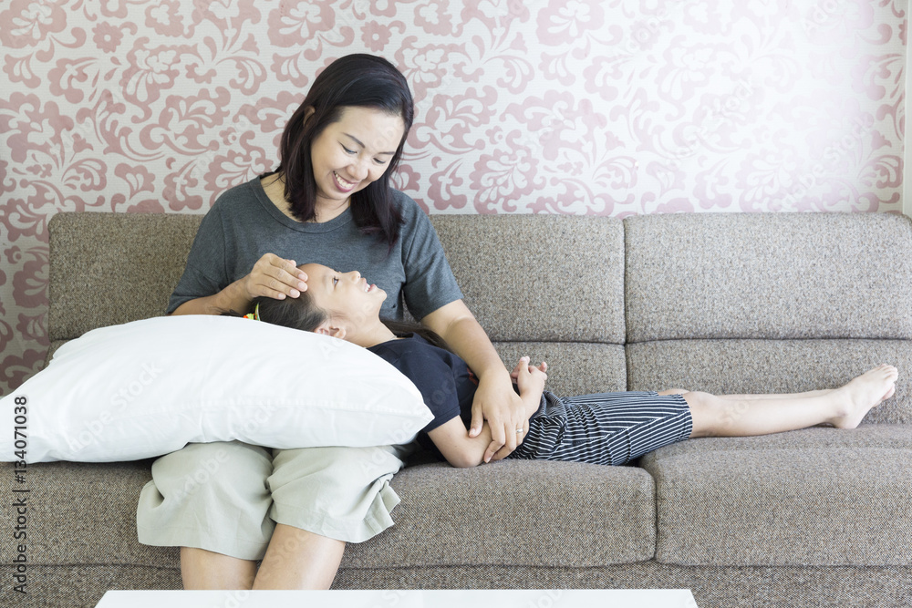 Daughter sleep with pillow on mother lap at sofa in living room Daughter sleep with pillow on mother lap at sofa in living room