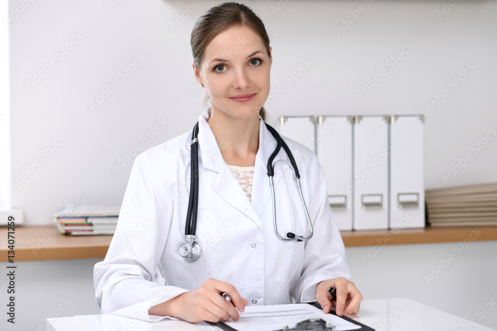 Doctor woman filling up medical form while sitting at the desk. Medicine and health care concept Doctor woman filling up medical form while sitting at the desk. Medicine and health care concept
