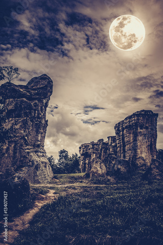 Boulders against sky with clouds and beautiful full moon at night