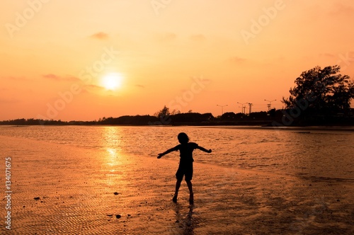 Silhouette of girl running on the beach at sunset © maybeiii