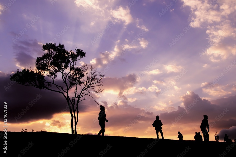 Silhouette of people walking on the hill with dramatic sky