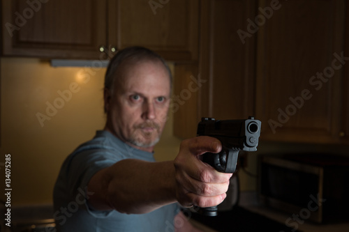 Man with handgun in kitchen, Gun in focus only