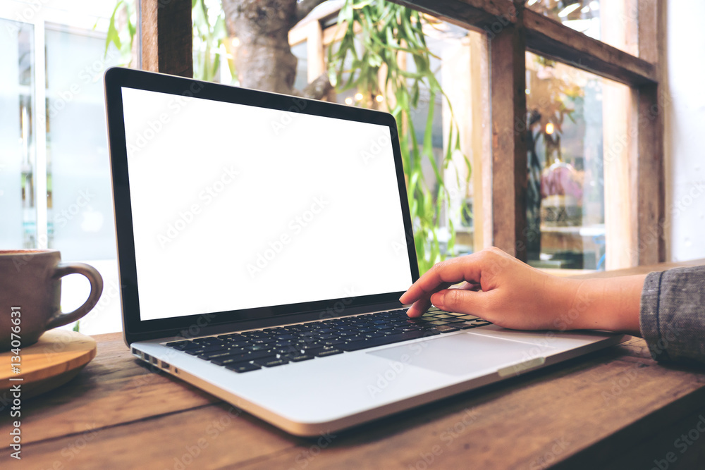 Mockup image of hand using laptop with blank white screen on vintage ...