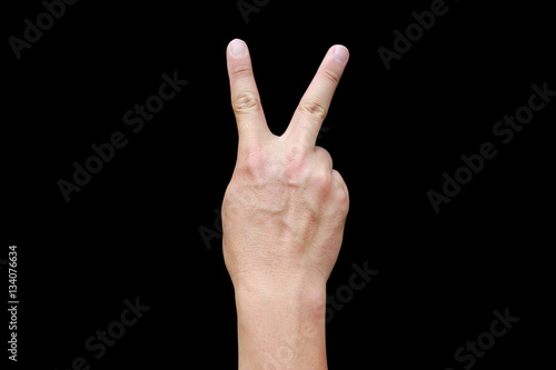 A hand shows in signal of scissors on black background. Hand with two fingers up in the peace or victory symbol. Also the sign for the letter V in sign language.