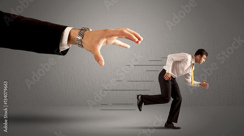 Photos Businessman running away from a huge hand
