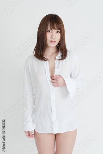 白いシャツを着たセクシーな女性。この女性は、脚の素肌を見せています。スタジオ撮影。白背景。