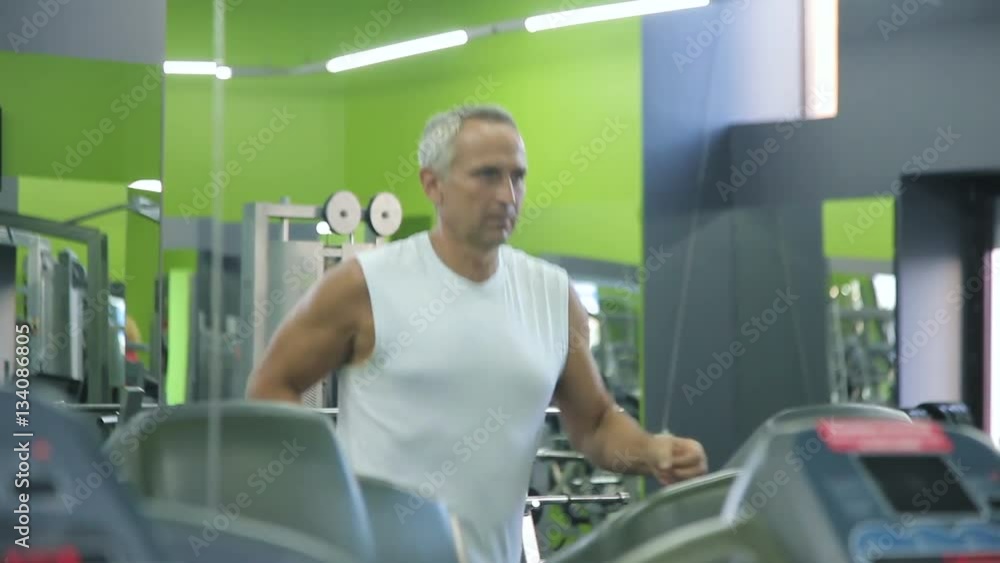 Old man runs on a treadmill Old man runs on a treadmill