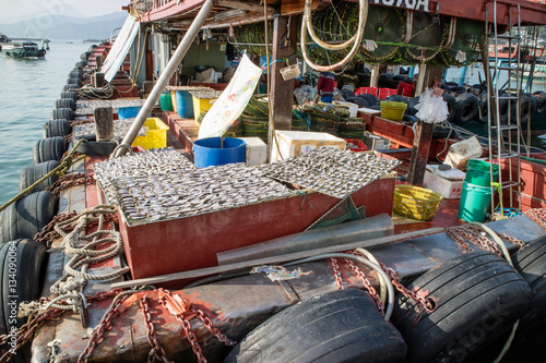 Fishing boat and its drying fish under the sun
