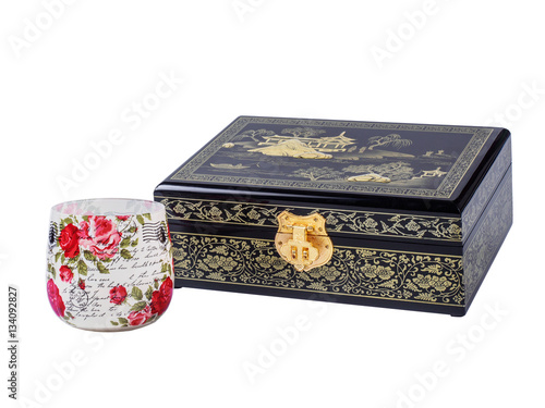 Picture of the wooden jewel-box with painting on wood and golden lock near decoupage glass isolated on white background. Painted pattern on closed box for bijouterie. Side view.