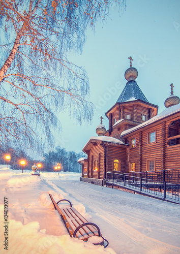 winter night landscape with old rural wooden Church and bench un