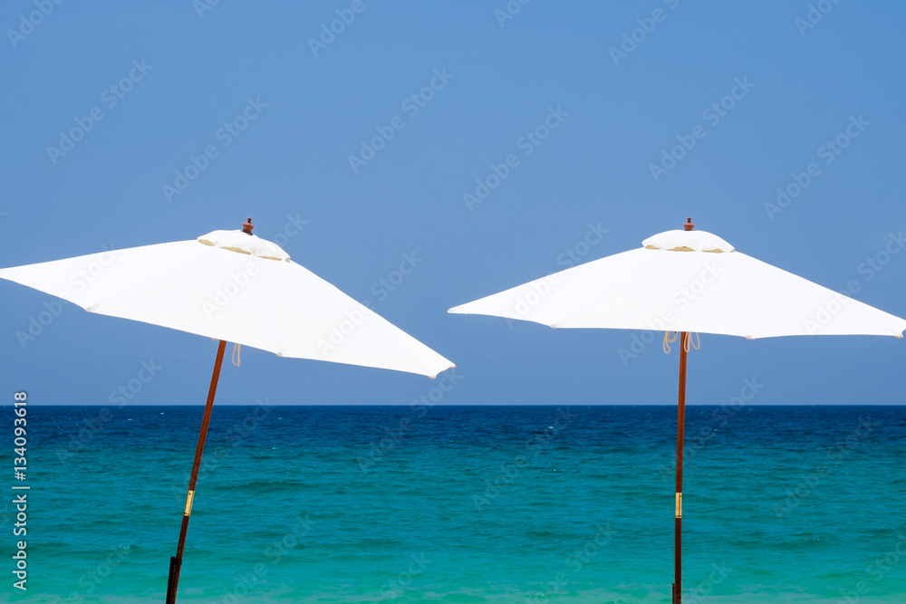 White beach umbrella on a sunny day against sea background.